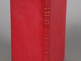 a red book sitting on top of a table next to a gray wall