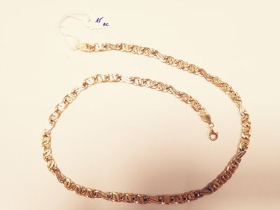 a gold chain with a heart on it on a white surface