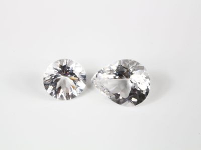 une paire de boucles d'oreilles en diamant blanc posées sur une surface blanche