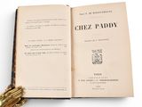 an open book sitting on top of a table next to a gold glove
