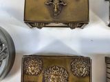 four pieces of antique brass are displayed on a white surface