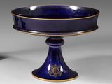 un bol bleu sur un piédestal avec une décoration en or