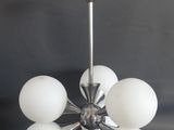 une image d'un lustre avec des boules de verre blanches suspendues au plafond