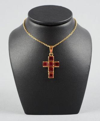 un collier avec une croix dorée et rouge autour du cou d'un mannequin
