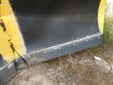 a black and yellow snow plow sitting on the ground