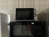two microwaves and a refrigerator in a small kitchen