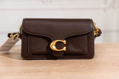 a small brown purse with a gold buckle on a wooden table