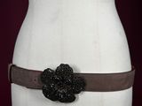 a close up of a mannequin torso wearing a belt with a flower on it