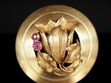 une image montrant un gros plan d'une broche en or ornée d'une fleur