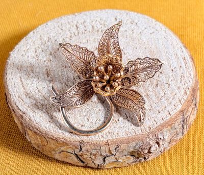 a silver ring with a flower on it sitting on a piece of wood