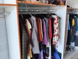 a closet full of clothes and a cat sitting on the floor