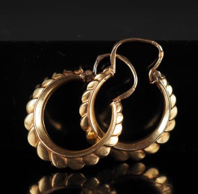 une paire de boucles d'oreilles en or sur une surface noire