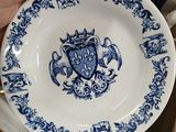 a person holding a blue and white plate with a coat of arms on it