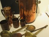 de nombreux objets en cuivre posés sur une table à côté d'un tableau noir