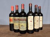 six bottles of red wine are lined up on a wooden table