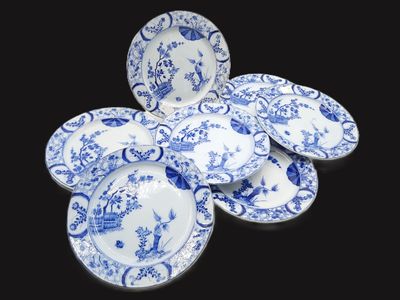 several blue and white plates are arranged on a black surface