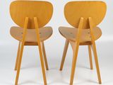 two wooden chairs sitting next to each other on a white surface