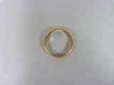 une bague en or posée sur une surface blanche, sur fond blanc