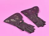 une paire de gants en cuir noir sur fond rose