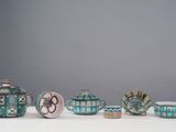 five teapots and two cups sitting on a table