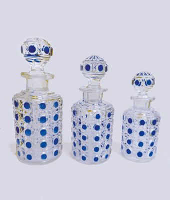 three glass bottles with blue dots are lined up on a white surface