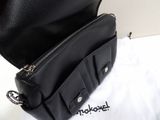 a black purse that is sitting on top of a white bag