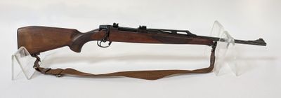 fusil exposé sur fond blanc, dans un présentoir en verre transparent