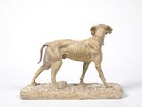 statue of a dog standing on a rock on a white background