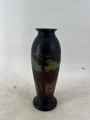 un vase noir orné d'un arbre, posé sur une surface blanche
