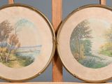Deux tableaux encadrés représentant des arbres et une rivière sont posés sur un chevalet en bois.