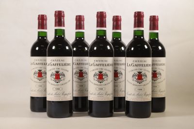 six bouteilles de vin rouge sont alignées sur une surface blanche