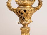 a gold vase with a bird on top of it