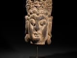 une tête de Bouddha sculptée posée sur un socle