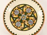 a green and yellow plate with a flower design on it