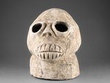 un gros plan d'un masque en pierre sur fond gris