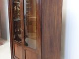 a wooden cabinet with a glass door in a room