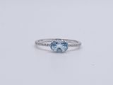 a white gold ring with a blue topaz stone surrounded by diamonds