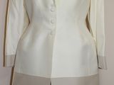 une veste blanche sur un mannequin, avec une jupe marron