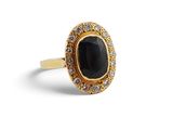 gros plan d'une bague avec une pierre noire entourée de diamants blancs