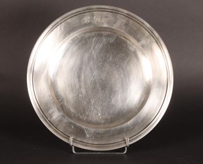 assiette en argent sur un support, sur fond noir, avec un fond noir