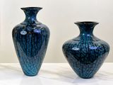 two blue vases sitting on a table in front of a painting