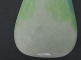 a green and white vase sitting on a black surface