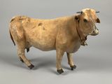 statue of a cow with a bell on a gray background