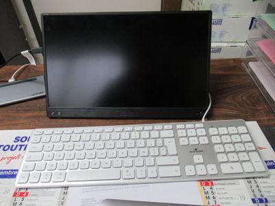 un ordinateur portable posé sur un bureau, à côté d'un clavier