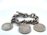 un bracelet en argent orné de pièces, posé sur un fond blanc