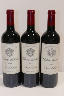 trois bouteilles de vin rouge sont alignées sur une surface blanche