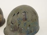 pair of wwii era german steel helmets on a white background