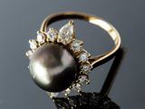 a close up of a black pearl and diamond ring on a black surface