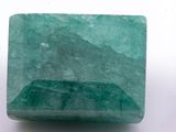 a close up of a green emerald stone on a white surface