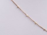 a close up of a gold chain necklace with a single diamond